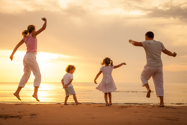 Happy family jumping on the beach on the dawn time